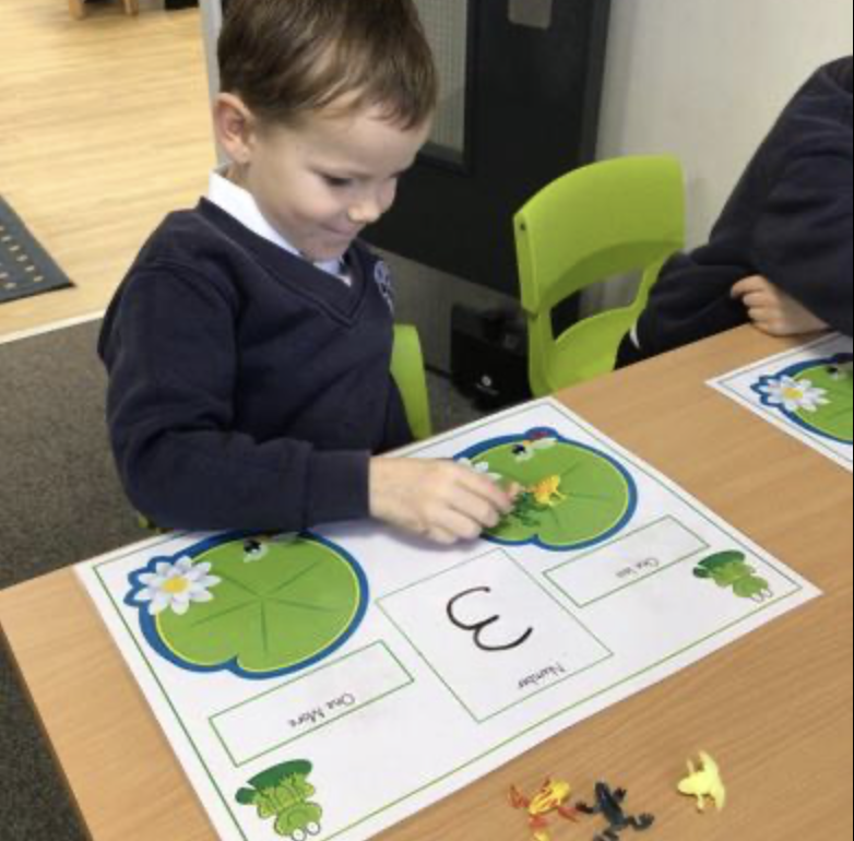 A young boy is doing some maths on a worksheet