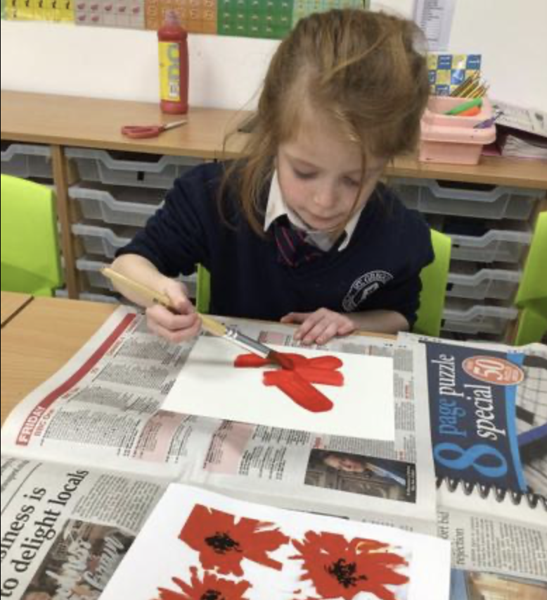 A young girl is sat painting a picture of a flower